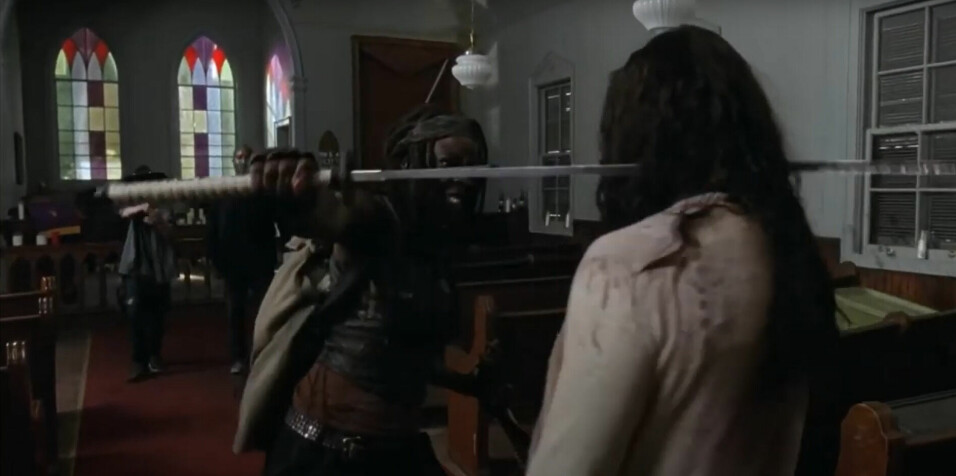 Utsnitt fra 'The Walking Dead' sesong 5, episode 8. Hannah Betts er nærmest kamera, med en Katana gjennom hodet.